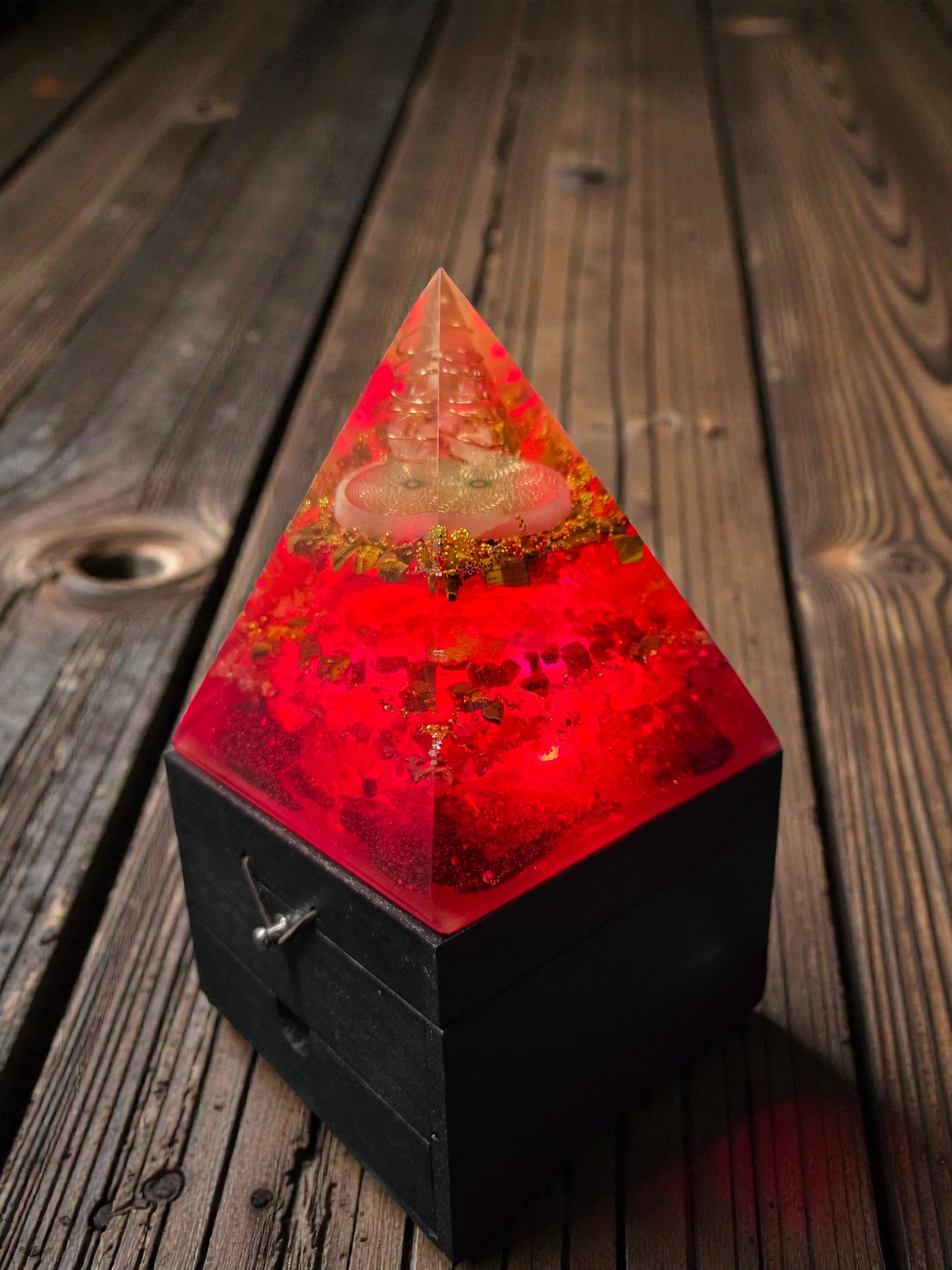 Pyramid-shaped lamp with red glow on a wooden surface