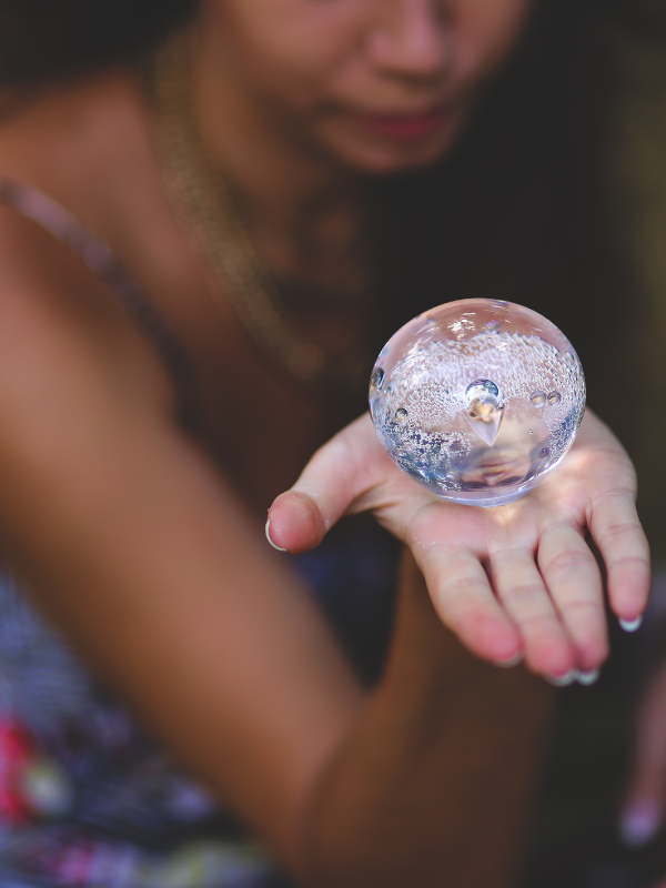 Clear quartz crystal sphere held in hand, used for spiritual home decor