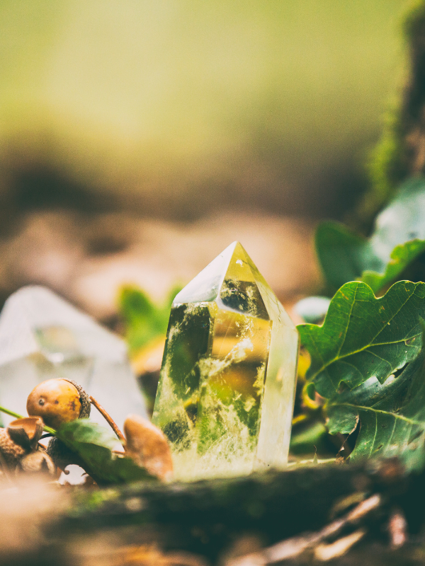 Green aventurine crystal pyramid on mossy forest background symbolizing abundance and prosperity.