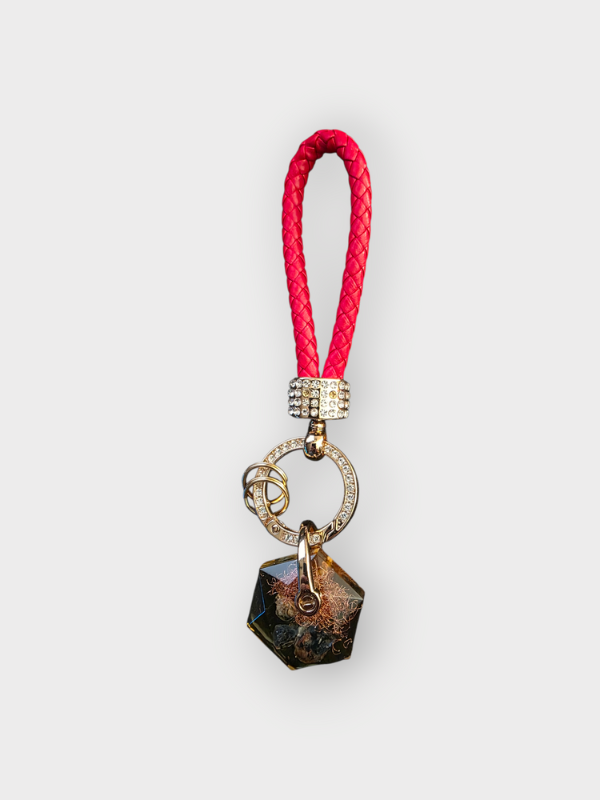 Keychain with red braided cord and geometric pendant on a white background