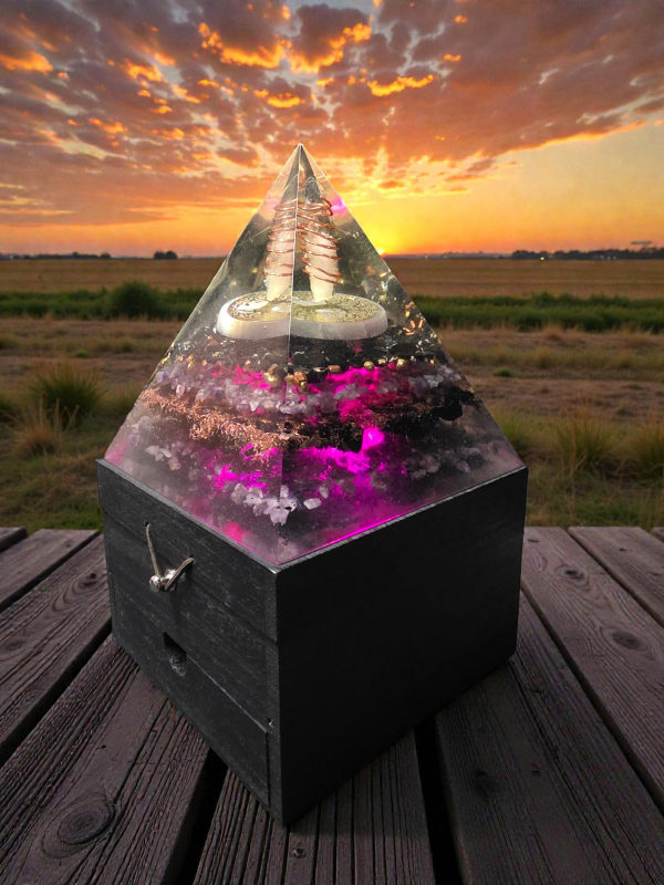 Pyramid-shaped crystal with LED lights on a wooden surface during sunset.