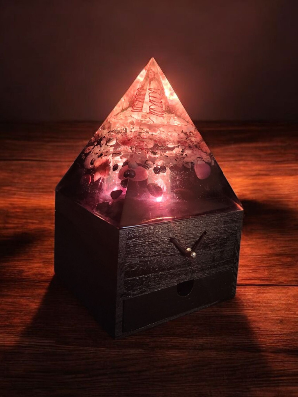 Celestial Drift orgonite lamp glowing with pink and purple light, featuring clear quartz, amethyst and moonstone inside a resin pyramid on a wooden jewellery box.