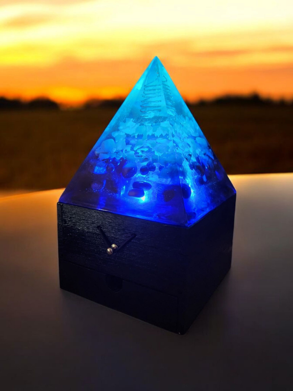 Blue and white orgonite pyramid lamp glowing at sunset, featuring crystals and a wooden jewellery box base – Celestial Flow Orgonite Lamp by SoulStone Designs.