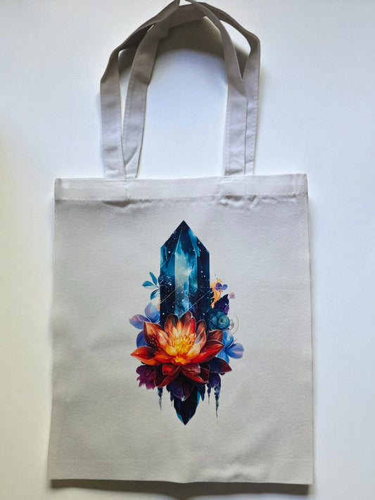 Canvas tote bag with a blue quartz crystal and vibrant lotus flower design on a light background