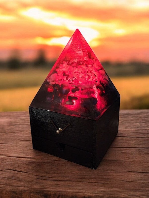 Soul Stone Designs red orgonite pyramid lamp with crystals and copper coil on a wooden box, glowing at sunset.