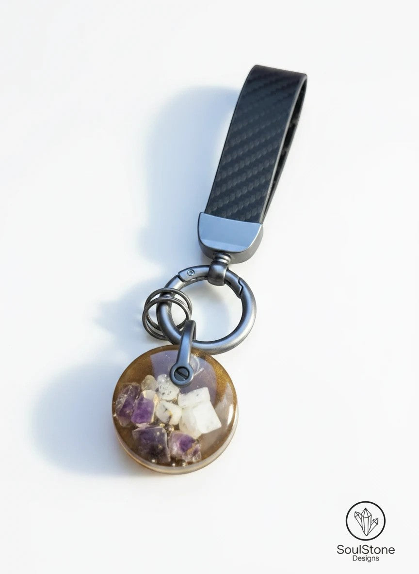 SoulStone Designs mini orgonite keychain with amethyst and moonstone crystals embedded in resin. Features a carbon fiber strap.