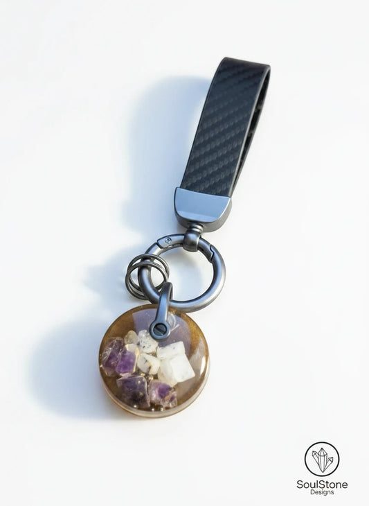 SoulStone Designs mini orgonite keychain with amethyst and moonstone crystals embedded in resin. Features a carbon fiber strap.