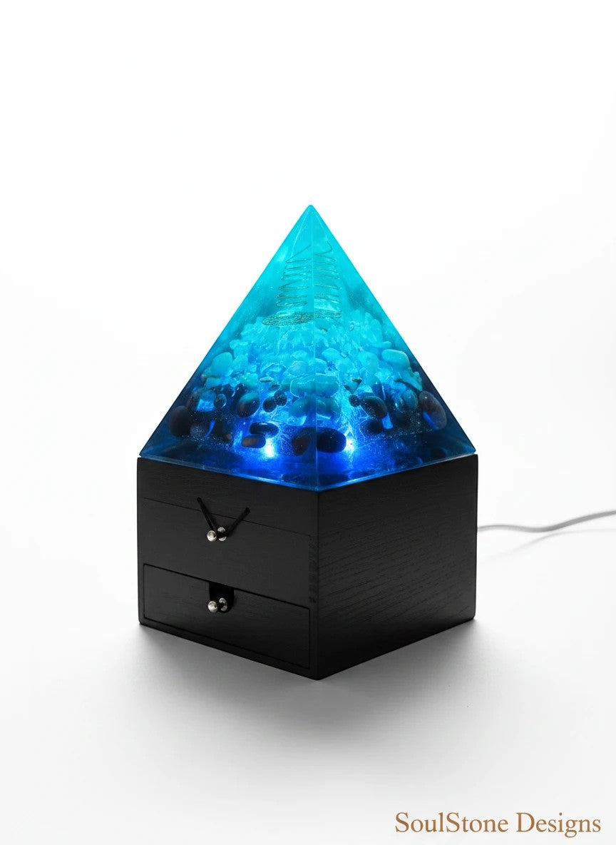 SoulStone Designs blue orgonite pyramid lamp with crystals and copper coil, on a wooden box base.