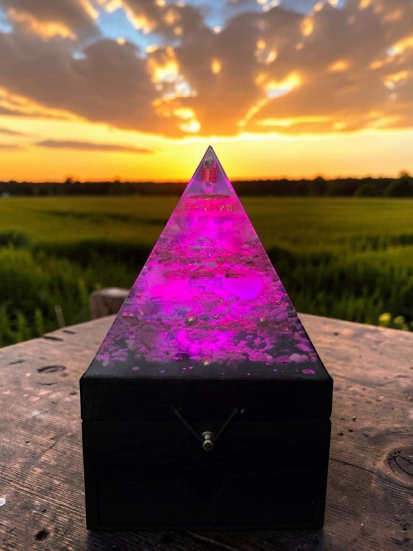 SoulStone Designs Prism of Clarity orgonite lamp with multicoloured LED light on a wooden box at sunset.