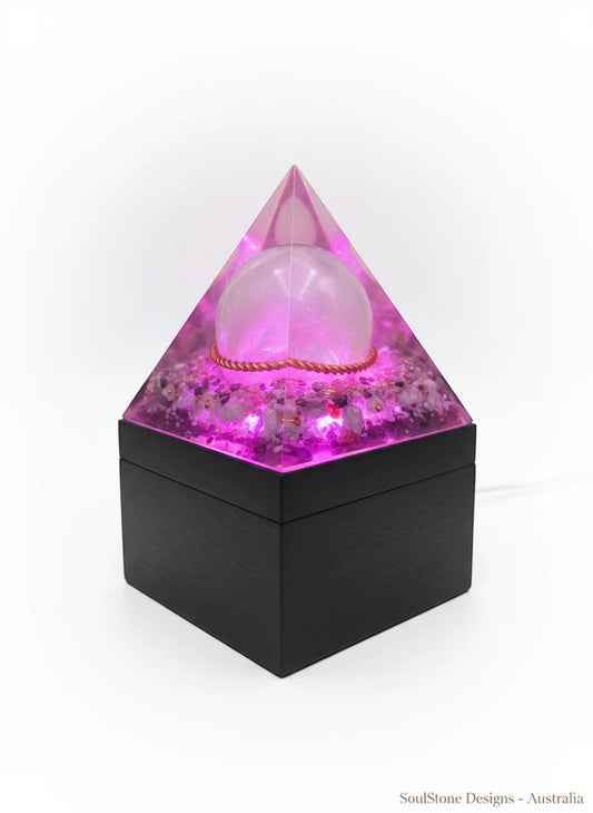 SoulStone Designs Ocean Serenity orgonite pyramid lamp with Selenite sphere, Lepidolite, Blue Calcite, Aquamarine, and copper ring, glowing pink.