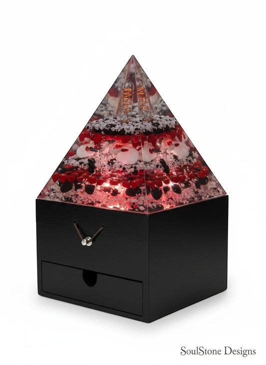 SoulStone Designs Aegis Root orgonite pyramid lamp with red, black, and white stones, copper coils, and a black wooden base with a drawer.