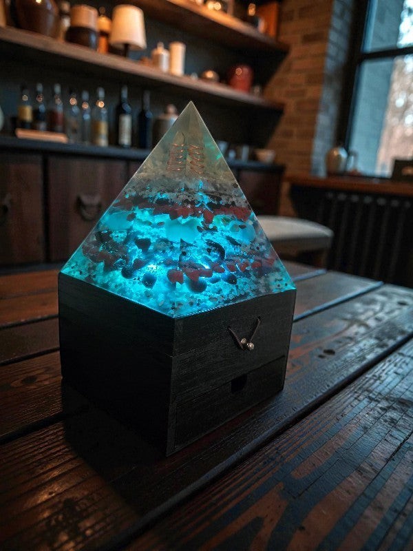 Soul Stone Designs Aegis Root orgonite pyramid lamp with blue light, clear quartz, copper coil, red jasper, and black stones.