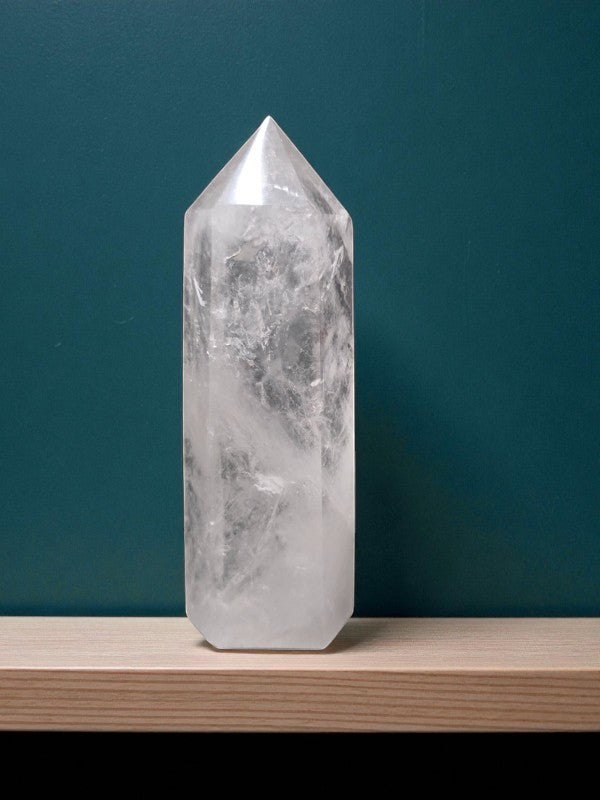 Soul Stone Designs clear quartz tower crystal with internal inclusions, polished to a point, on a wooden shelf.