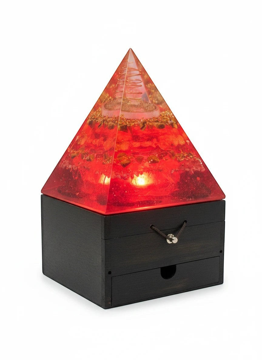 Soul Stone Designs red orgonite pyramid lamp with copper torus and crystals, on a wooden base with drawer.